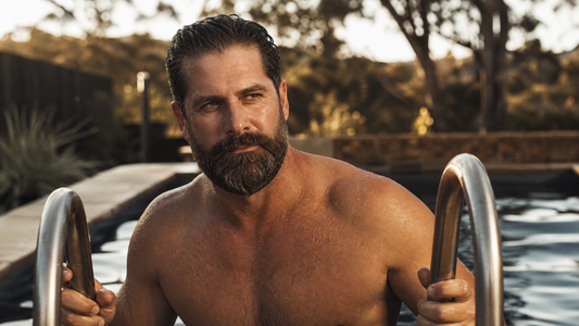 Bearded man with a wet beard climbing out of a swimming pool at golden hour